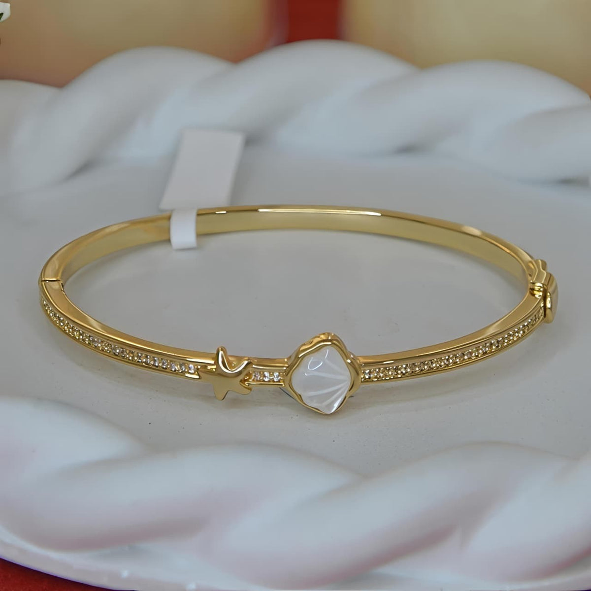 Aurevia Fashion Jewellery gold-tone bangle featuring a mother of pearl shell inlay and a delicate starfish accent.