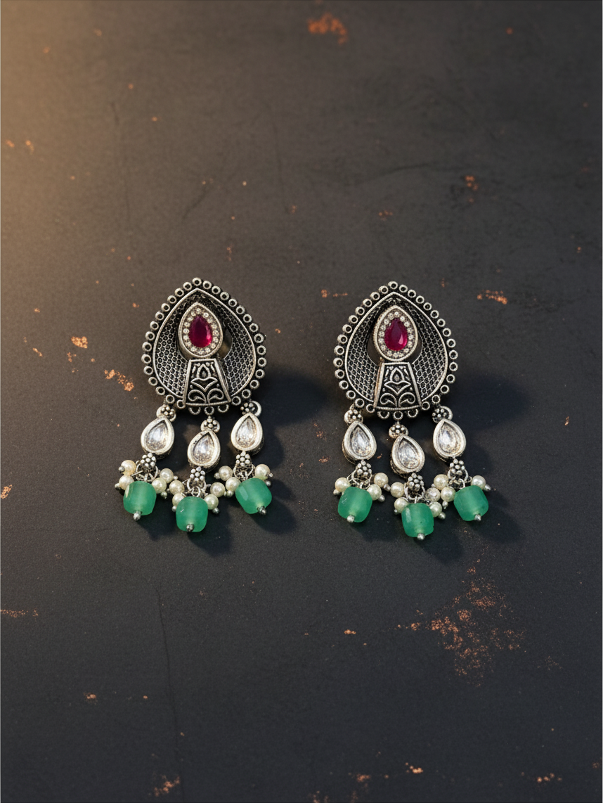 Aurevia Fashion Jewellery Jhansi Aura oxidized silver earrings with ruby red stones, clear crystals, and green beads.