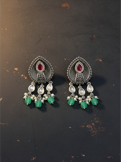 Aurevia Fashion Jewellery Jhansi Aura oxidized silver earrings with ruby red stones, clear crystals, and green beads.