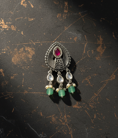Aurevia Fashion Jewellery Jhansi Aura oxidized silver pendant with a central ruby, white stones, and green beads.