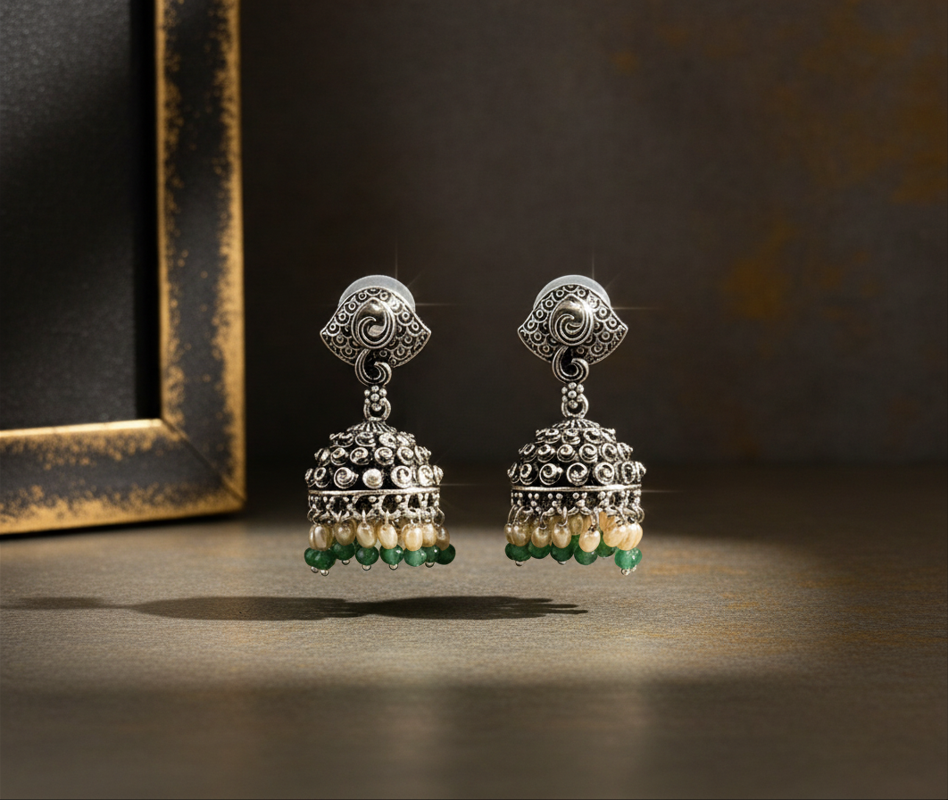 Aurevia Fashion Jewellery Jhansi Noor silver jhumka earrings with intricate metalwork, white pearls, and green beads.