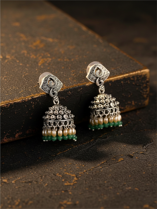 Aurevia Fashion Jewellery Jhansi Noor silver jhumka earrings with intricate metalwork, pearl, and green bead accents.