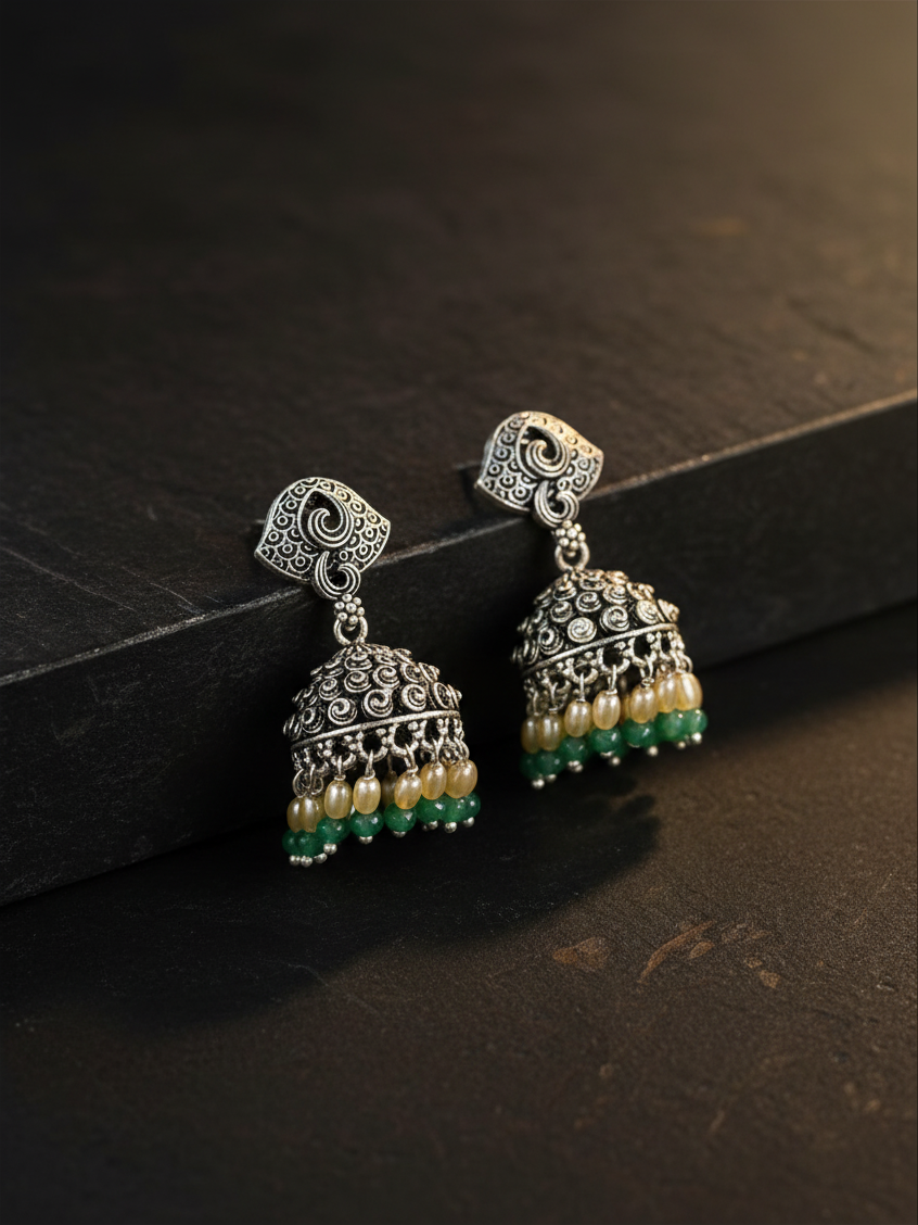 Aurevia Fashion Jewellery Jhansi Noor silver jhumka earrings with intricate metalwork, cream pearls, and green beads.
