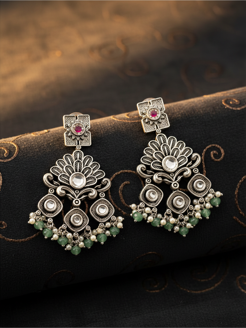 Aurevia Fashion Jewellery Jhansi Regal silver-toned drop earrings with floral motifs, pink stones, and green beads.