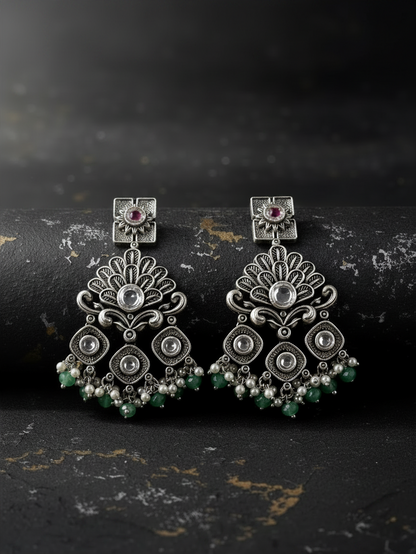Aurevia Fashion Jewellery Jhansi Regal silver-toned drop earrings with intricate filigree, pink stones, and green beads.