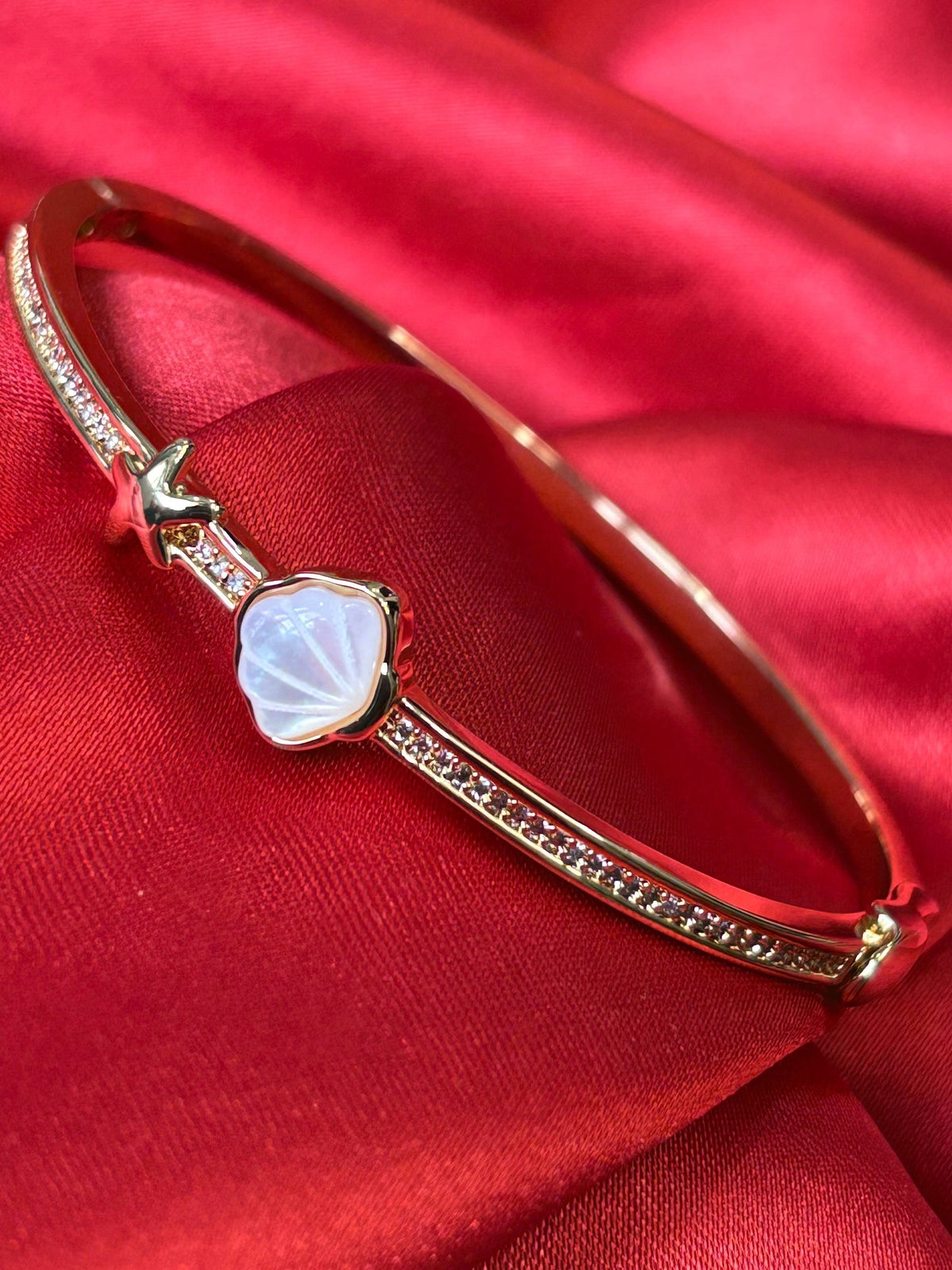 Aurevia Fashion Jewellery gold-tone bangle featuring an iridescent mother of pearl shell and starfish accent