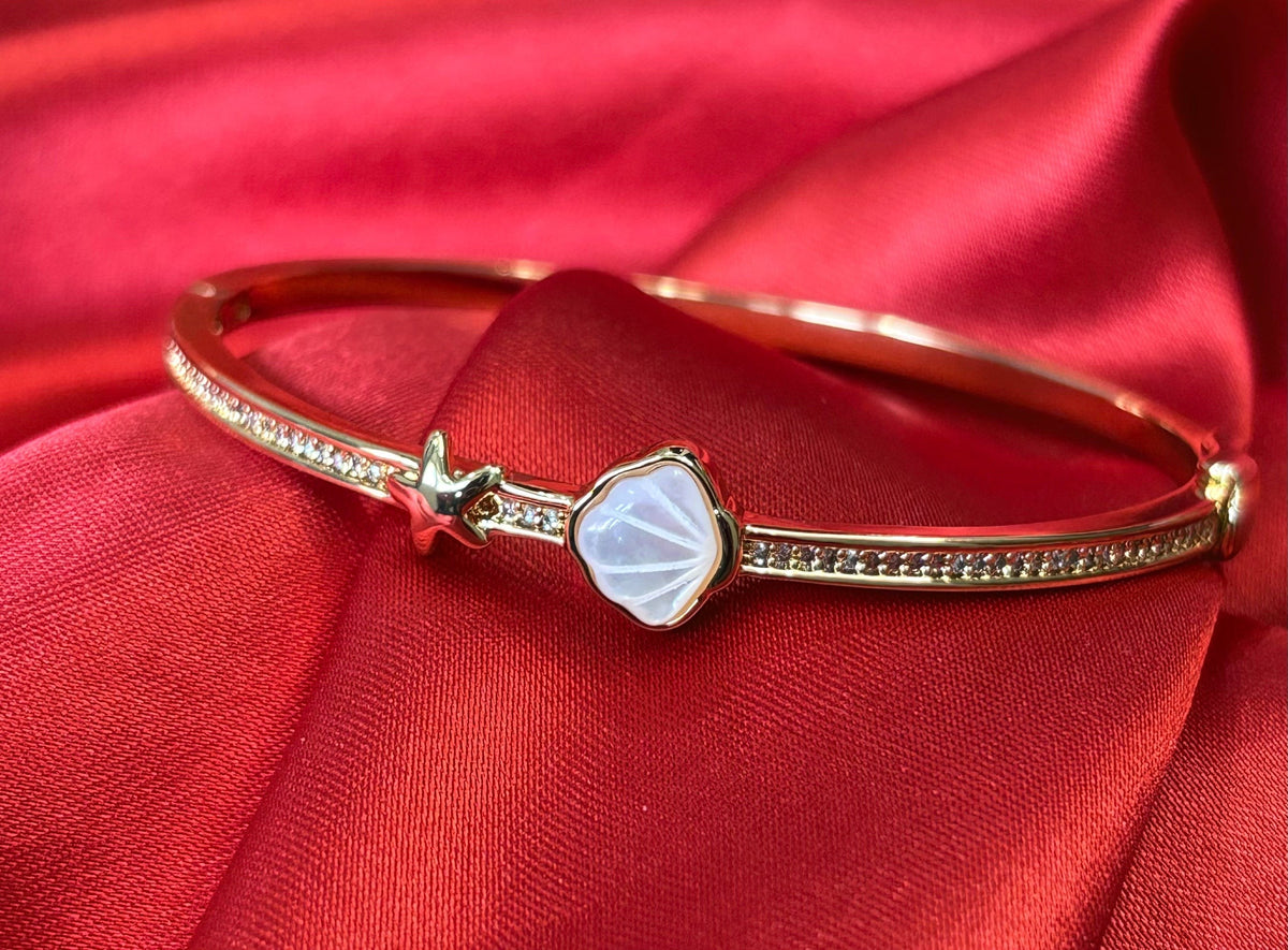 Aurevia Fashion Jewellery rose gold bangle featuring a mother of pearl shell inlay and a delicate starfish accent.