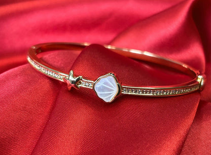 Aurevia Fashion Jewellery rose gold bangle featuring a mother of pearl shell inlay and a delicate starfish accent.