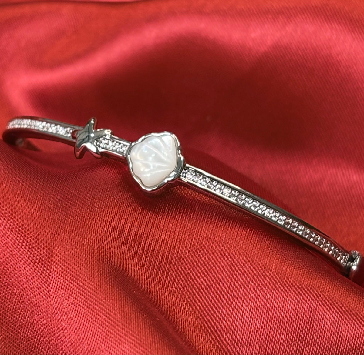 Aurevia Fashion Jewellery bangle featuring an iridescent mother of pearl shell and starfish accent on a red fabric