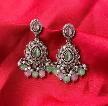 Aurevia Fashion Jewellery Noor multi-color kundan drop earrings with pastel gemstones and pearls on red silk fabric.