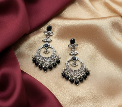Aurevia Fashion Jewellery Noorika black chandbali earrings featuring a crescent moon design on a satin fabric backdrop