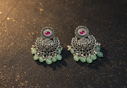Aurevia Fashion Jewellery Jhansi Grace oxidized silver earrings with pink stones, green beads, and pearl accents.