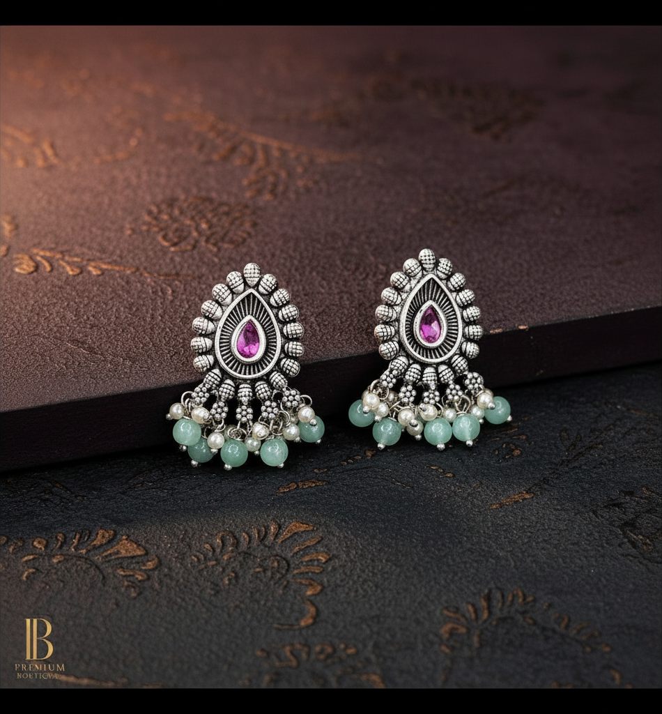 Aurevia Fashion Jewellery Jhansi Majesty oxidized silver stud earrings with pink teardrop stones and mint bead dangles.