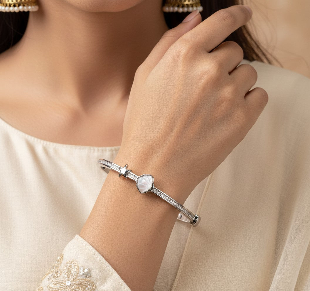 Aurevia Fashion Jewellery bangle featuring a mother of pearl shell and starfish charm on a polished silver-tone band.