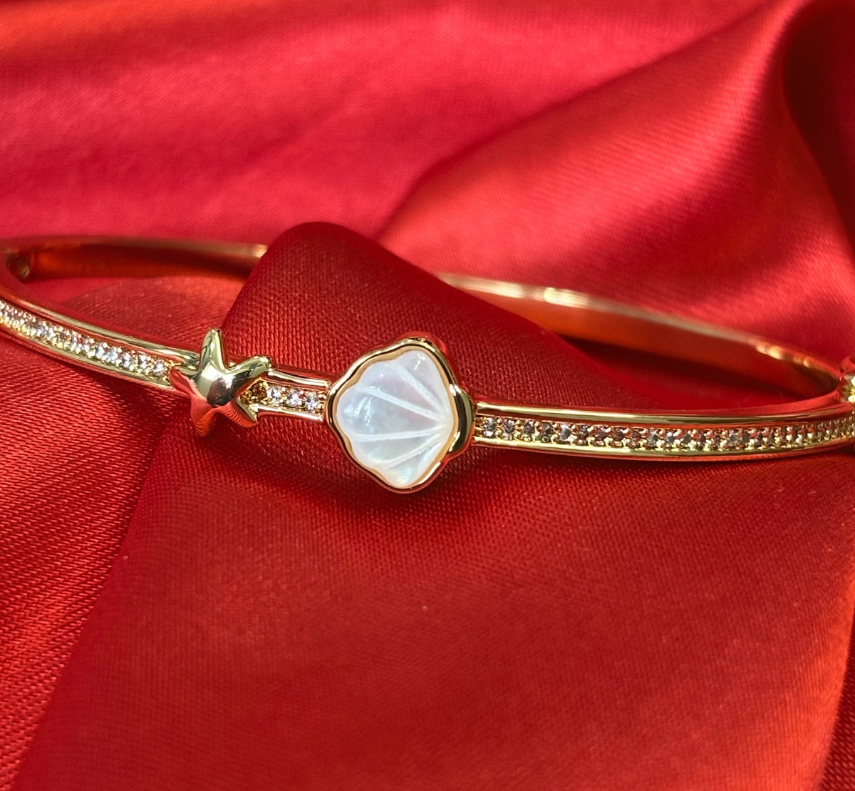 Aurevia Fashion Jewellery gold-tone bangle featuring a mother of pearl shell, starfish accent, and crystal details.