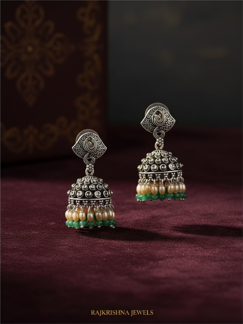Aurevia Fashion Jewellery Jhansi Noor silver jhumka earrings with pearl and green bead accents on velvet background
